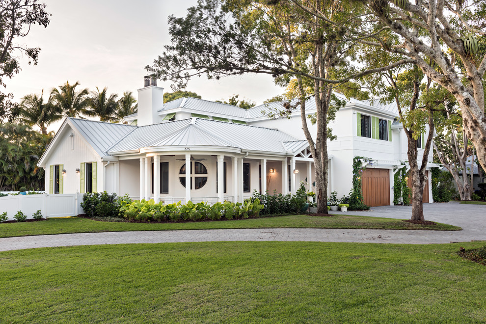 Inspiration for a beach style two-storey white house exterior in Miami with a hip roof and a metal roof.