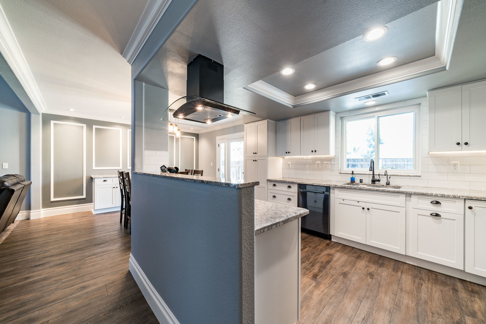 Mid-sized transitional u-shaped dark wood floor and brown floor eat-in kitchen photo with an undermount sink, shaker cabinets, white cabinets, granite countertops, white backsplash, subway tile backsplash, stainless steel appliances and an island