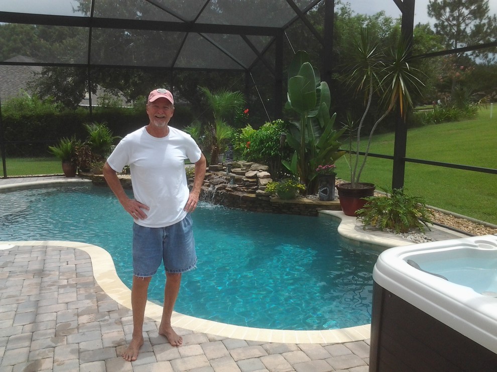 Mid-sized arts and crafts backyard kidney-shaped pool in Orlando with a water feature and concrete pavers.