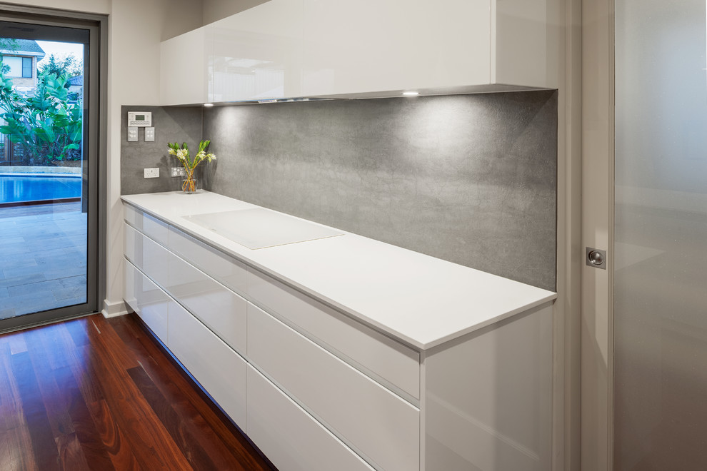 Design ideas for a large modern single-wall separate kitchen in Perth with louvered cabinets, white cabinets, granite benchtops, beige splashback, cement tile splashback, white appliances, medium hardwood floors and with island.