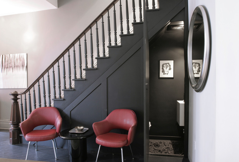 Photo of a small eclectic foyer in New York with black walls, painted wood floors and a black front door.