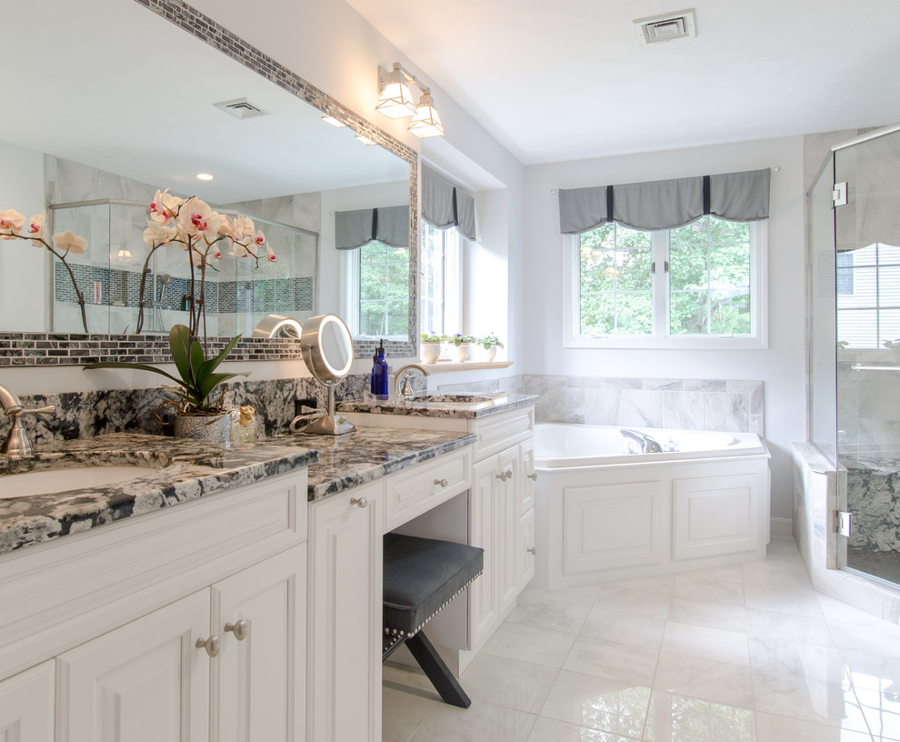 This is an example of a traditional bathroom in Boston with raised-panel cabinets, white cabinets, a corner tub, a corner shower and white walls.