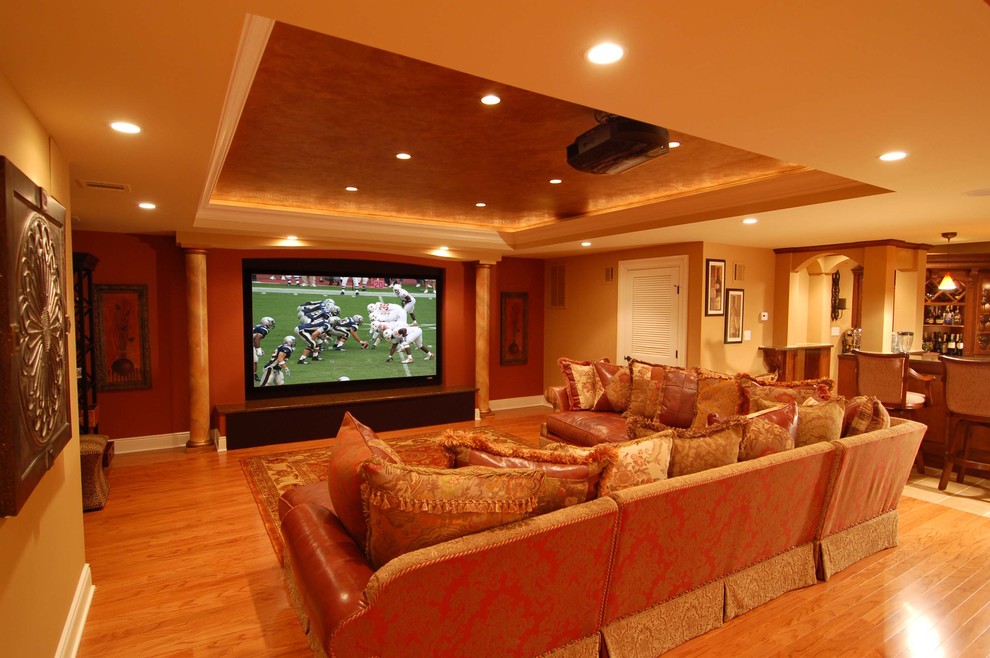 This is an example of a large contemporary enclosed home theatre in New York with beige walls, dark hardwood floors and a wall-mounted tv.