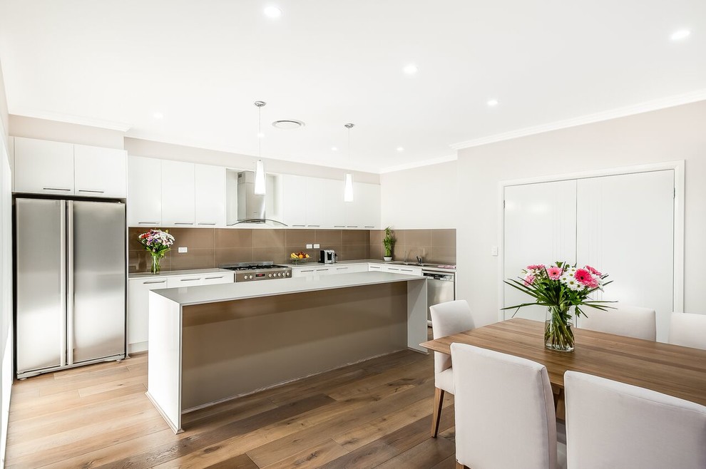 Inspiration for a large modern galley eat-in kitchen in Sydney with a double-bowl sink, white cabinets, quartz benchtops, beige splashback, ceramic splashback, stainless steel appliances, medium hardwood floors and with island.