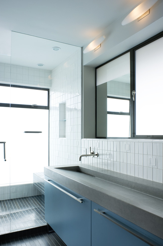 Photo of a modern bathroom in San Francisco with a trough sink, flat-panel cabinets, blue cabinets and white tile.