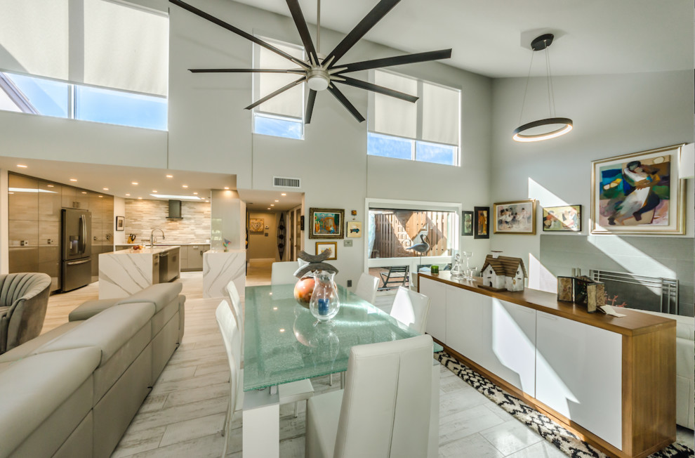 Photo of a large eclectic open plan dining in Tampa with white walls, porcelain floors, a wood stove, a plaster fireplace surround and white floor.