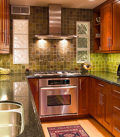 Mid-sized trendy u-shaped light wood floor enclosed kitchen photo with a double-bowl sink, recessed-panel cabinets, dark wood cabinets, green backsplash, stainless steel appliances, granite countertops, stone tile backsplash and no island