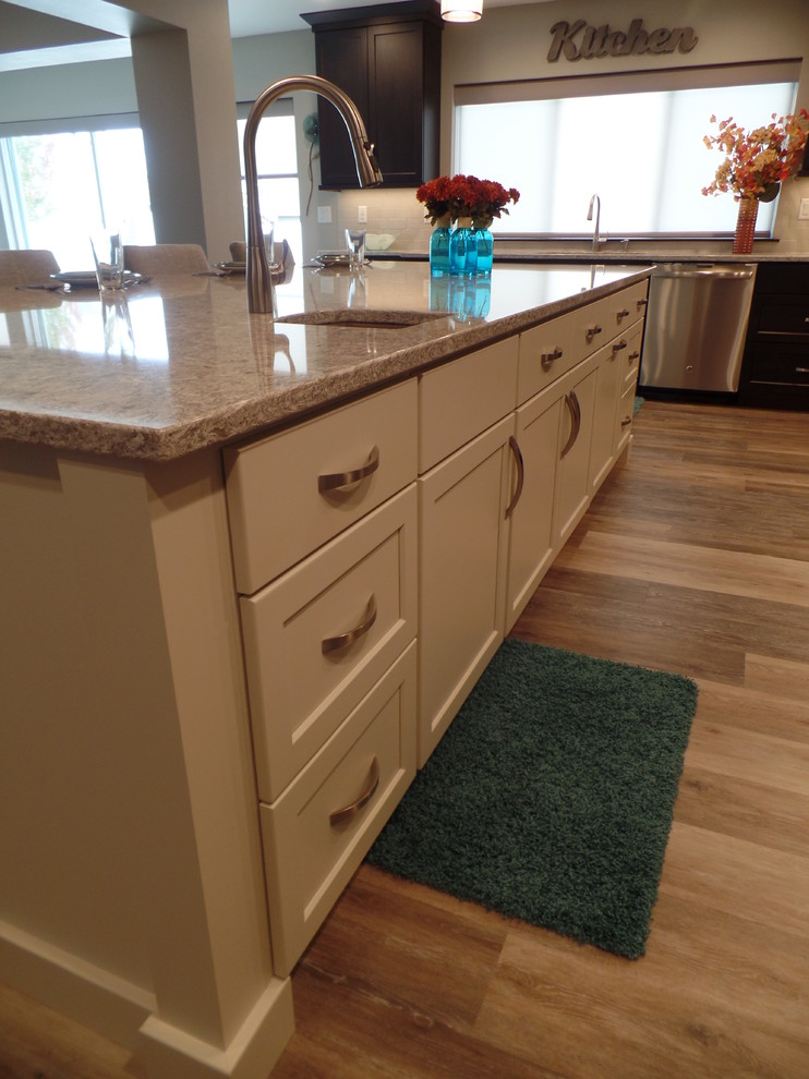 Eat-in kitchen - large transitional l-shaped medium tone wood floor and beige floor eat-in kitchen idea in Cedar Rapids with an undermount sink, shaker cabinets, dark wood cabinets, granite countertops, white backsplash, subway tile backsplash, stainless steel appliances and an island