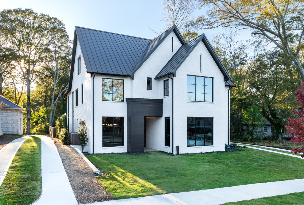 Contemporary white two-story brick exterior home idea in Other with a metal roof and a black roof