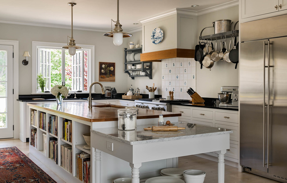 Design ideas for a mid-sized country u-shaped open plan kitchen in Bridgeport with shaker cabinets, white cabinets, granite benchtops, white splashback, stainless steel appliances, light hardwood floors, with island, beige floor, porcelain splashback and a farmhouse sink.