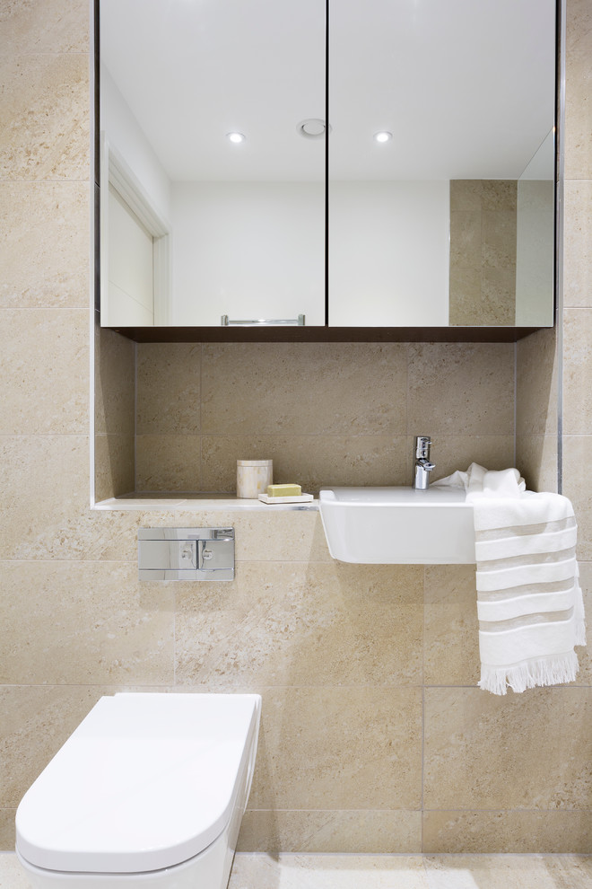 This is an example of a mid-sized contemporary bathroom in London with a wall-mount toilet, beige tile and a drop-in sink.