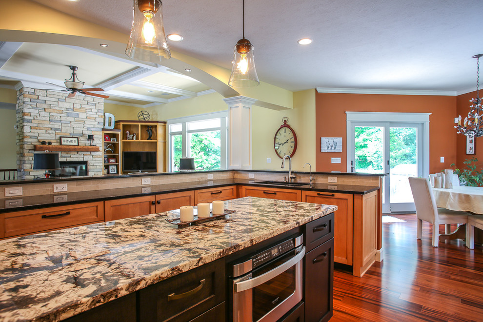 Example of a huge transitional medium tone wood floor kitchen design with an undermount sink, shaker cabinets, light wood cabinets, granite countertops, beige backsplash, porcelain backsplash, stainless steel appliances and an island
