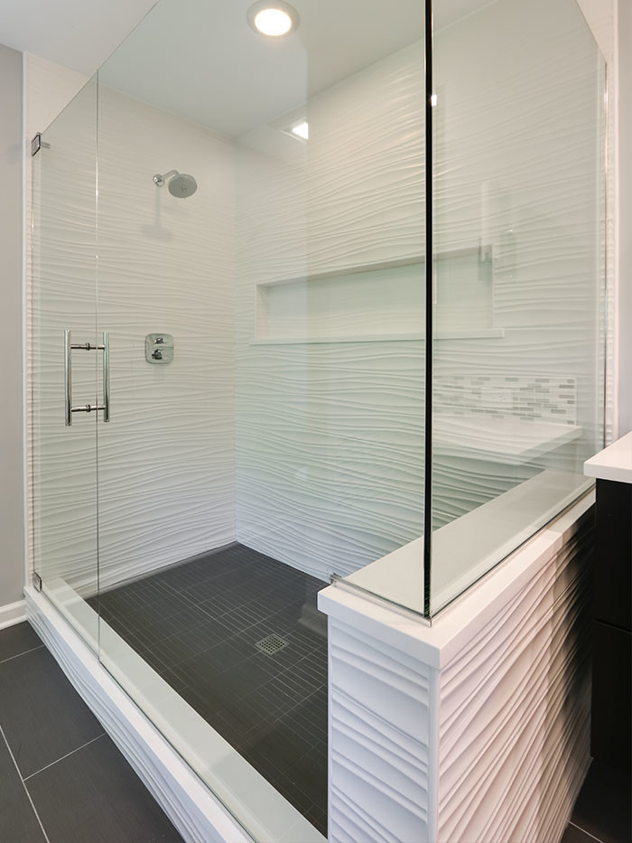 Photo of a large contemporary master bathroom in Chicago with flat-panel cabinets, dark wood cabinets, a drop-in tub, an open shower, a one-piece toilet, multi-coloured tile, glass tile, beige walls, porcelain floors, an undermount sink and engineered quartz benchtops.
