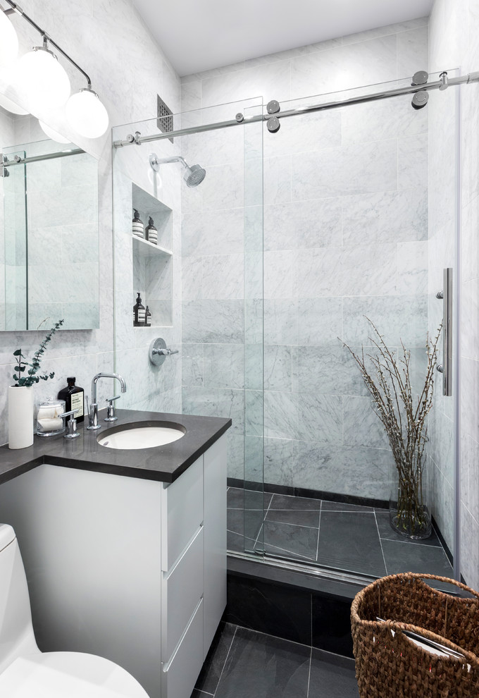 Small contemporary 3/4 bathroom in New York with flat-panel cabinets, white cabinets, an alcove shower, a one-piece toilet, white tile, an undermount sink, black floor, a sliding shower screen and marble.