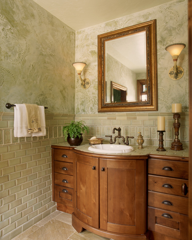 Mid-sized traditional powder room in Denver with a drop-in sink, subway tile, furniture-like cabinets, medium wood cabinets, green tile, green walls, ceramic floors, granite benchtops, beige floor and green benchtops.