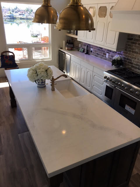 Mid-sized transitional single-wall kitchen photo in Austin with a farmhouse sink, raised-panel cabinets, white cabinets, stainless steel appliances and an island