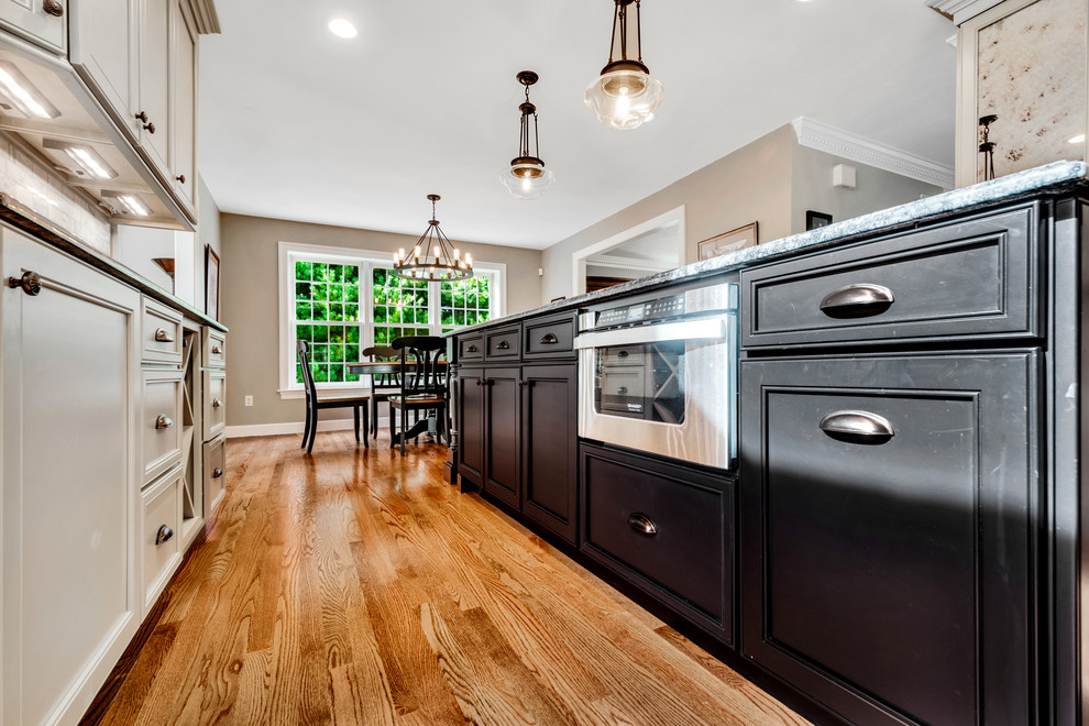 This is an example of a large transitional l-shaped eat-in kitchen in Boston with recessed-panel cabinets, grey cabinets, marble benchtops, grey splashback, subway tile splashback, stainless steel appliances, with island, an undermount sink, medium hardwood floors, brown floor and grey benchtop.