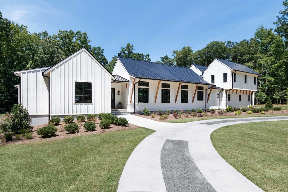 Photo of an expansive country white house exterior in Raleigh with a gable roof and a metal roof.