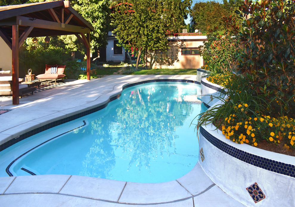 Design ideas for a large eclectic backyard pool in Los Angeles with concrete pavers.