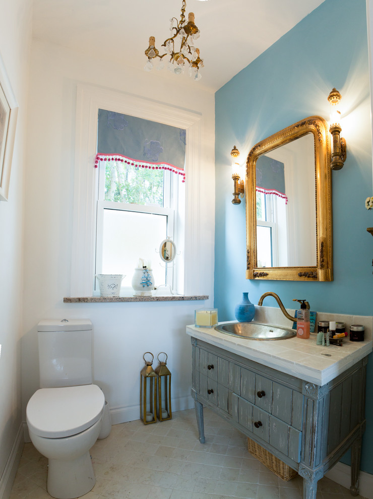 Bathroom - mid-sized traditional white tile and stone tile limestone floor bathroom idea in Cork with a console sink, blue cabinets, tile countertops, a one-piece toilet and blue walls