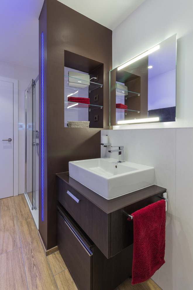 Photo of a mid-sized contemporary powder room in Nuremberg with dark wood cabinets, a wall-mount toilet, white tile, ceramic tile, white walls, medium hardwood floors and a vessel sink.