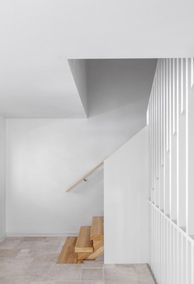 Foto på en mellanstor minimalistisk l-trappa i trä, med öppna sättsteg och räcke i trä