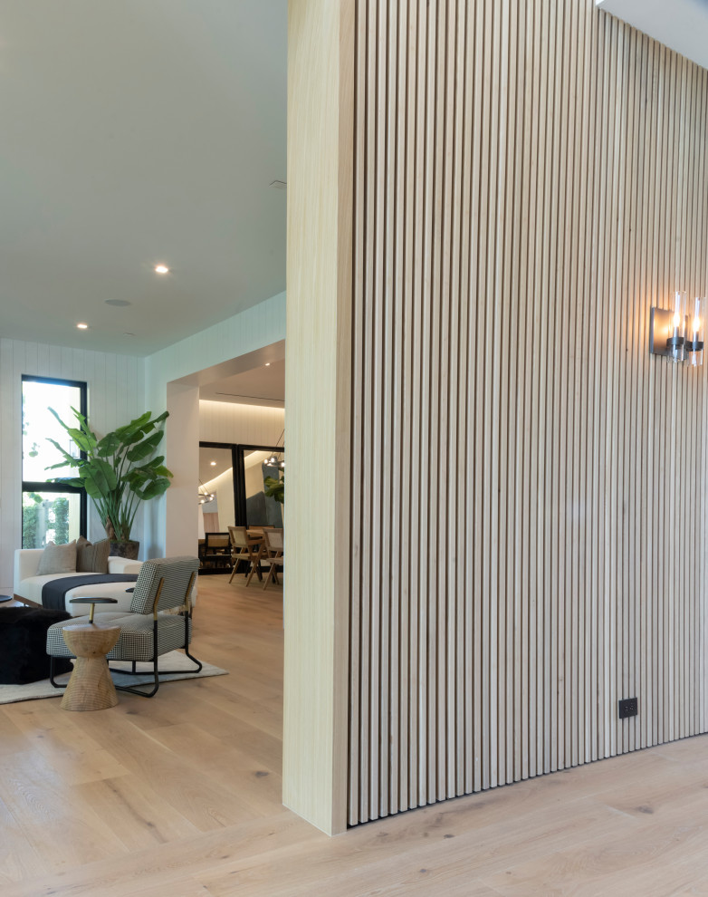 Foto de entrada moderna con paredes beige, suelo de madera clara y panelado