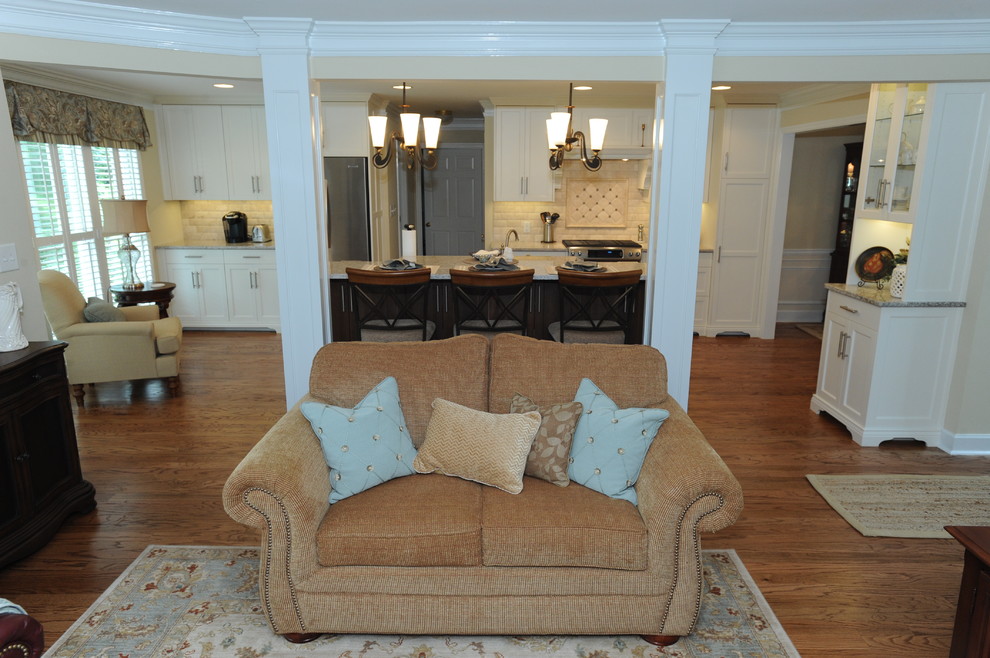 Example of a transitional medium tone wood floor kitchen design in Atlanta with an undermount sink, recessed-panel cabinets, quartz countertops, beige backsplash, stone tile backsplash, stainless steel appliances and an island