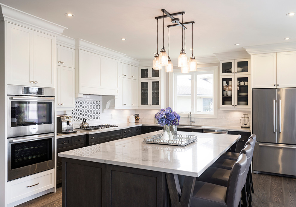 Example of a large transitional l-shaped dark wood floor open concept kitchen design in Toronto with an undermount sink, recessed-panel cabinets, white cabinets, quartzite countertops, white backsplash, subway tile backsplash, stainless steel appliances and an island