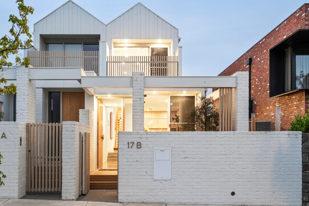This is an example of a mid-sized contemporary two-storey brick white townhouse exterior in Geelong with a gable roof.