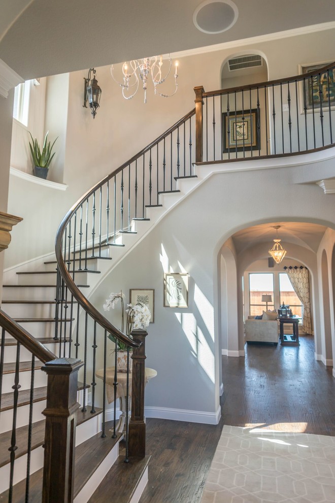This is an example of a large transitional wood curved staircase in Dallas with painted wood risers and mixed railing.
