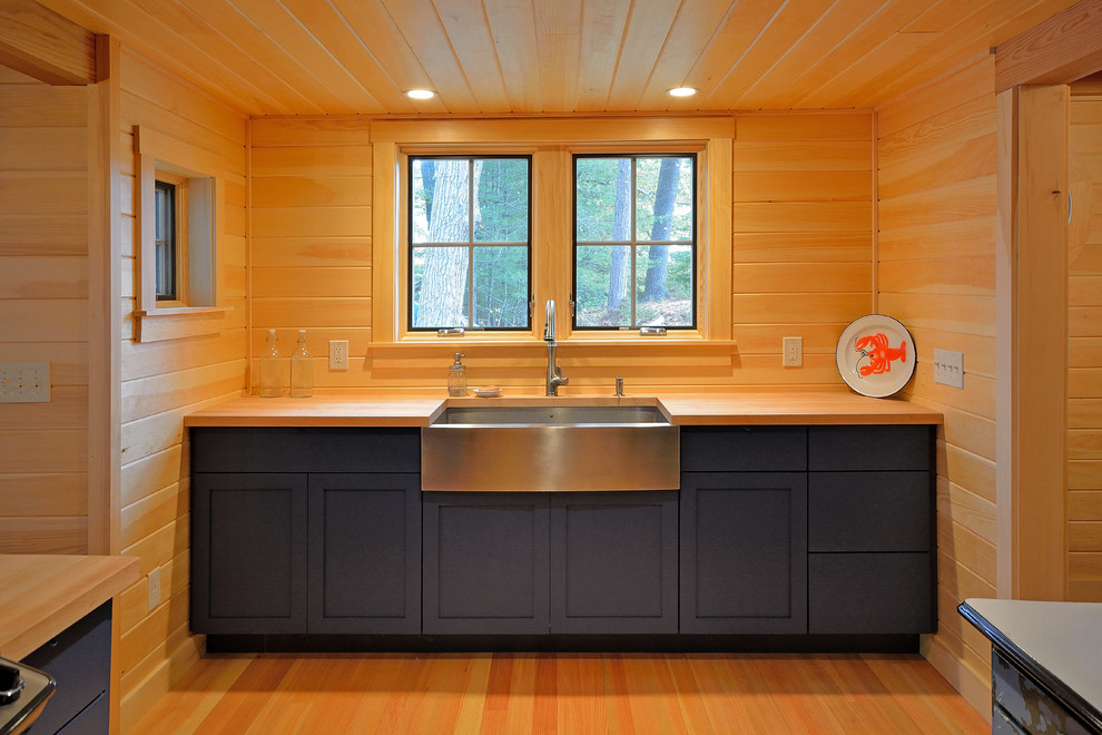 Photo of an eclectic u-shaped open plan kitchen in Portland Maine with a farmhouse sink, blue cabinets, wood benchtops, stainless steel appliances and medium hardwood floors.
