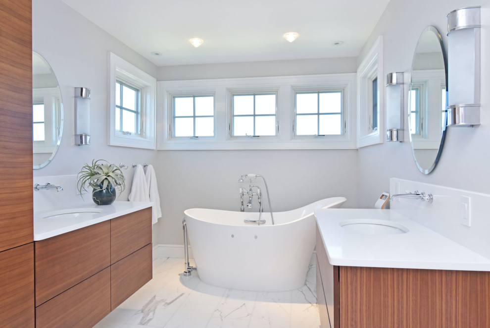 Design ideas for a mid-sized modern master bathroom in Providence with flat-panel cabinets, medium wood cabinets, a freestanding tub, a corner shower, white walls, marble floors, an undermount sink, engineered quartz benchtops, white floor, a hinged shower door and white benchtops.