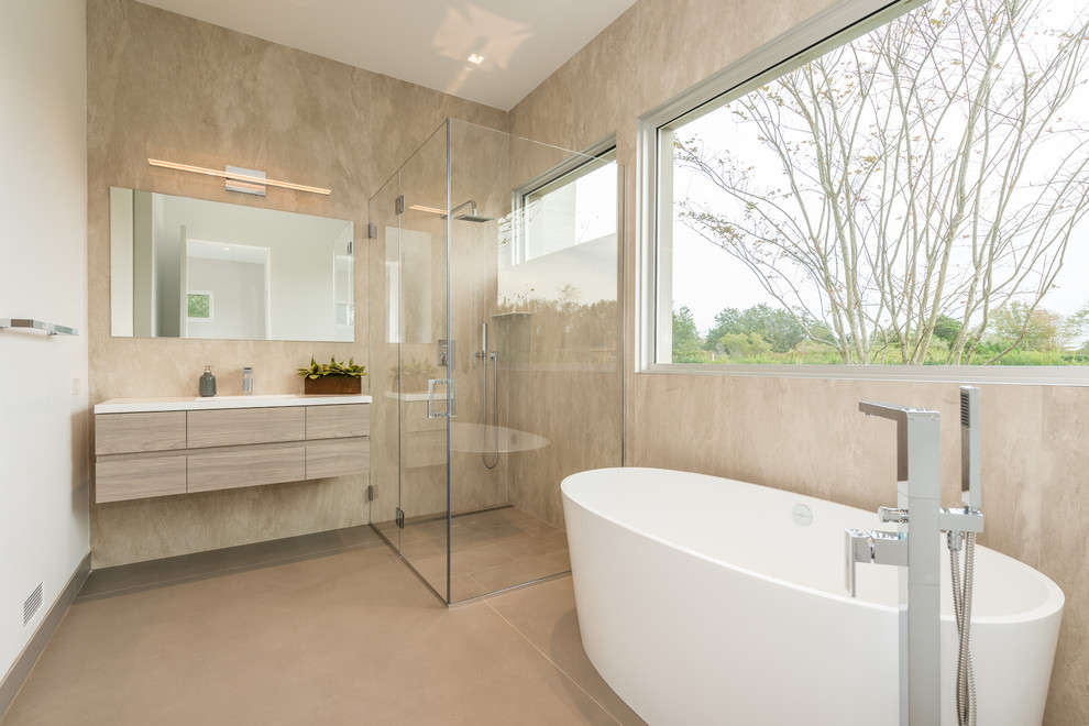 Contemporary master bathroom in New York with flat-panel cabinets, light wood cabinets, a freestanding tub, a corner shower, beige tile, beige walls, an undermount sink, beige floor, a hinged shower door and white benchtops.