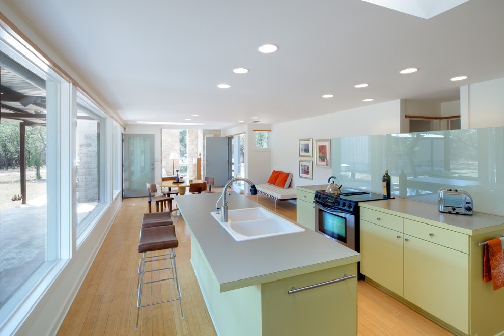 Photo of a modern open plan kitchen in Austin with a drop-in sink, yellow cabinets and glass sheet splashback.