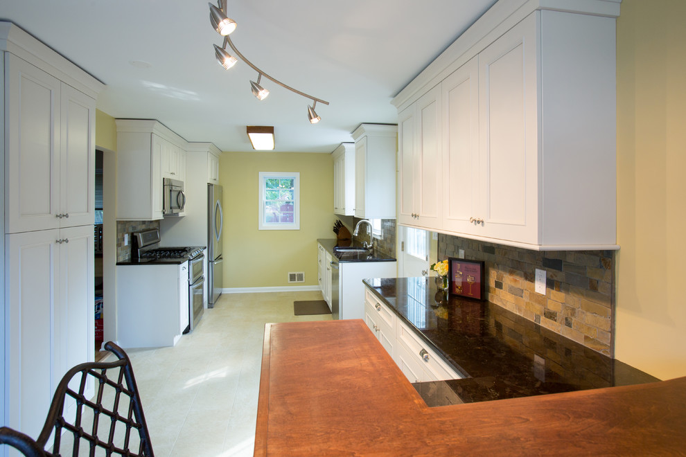 Photo of a mid-sized transitional galley eat-in kitchen in DC Metro with an undermount sink, shaker cabinets, white cabinets, granite benchtops, green splashback, slate splashback, stainless steel appliances, porcelain floors and a peninsula.