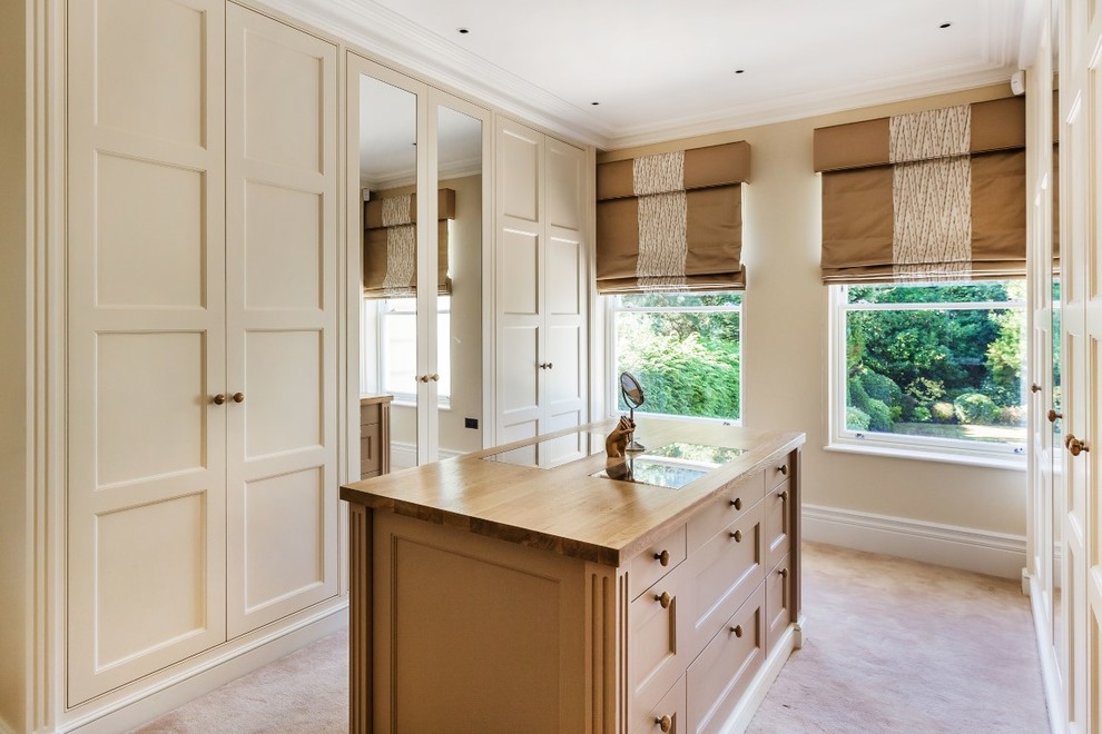 Traditional gender-neutral dressing room in Surrey with recessed-panel cabinets, beige cabinets, carpet and beige floor.