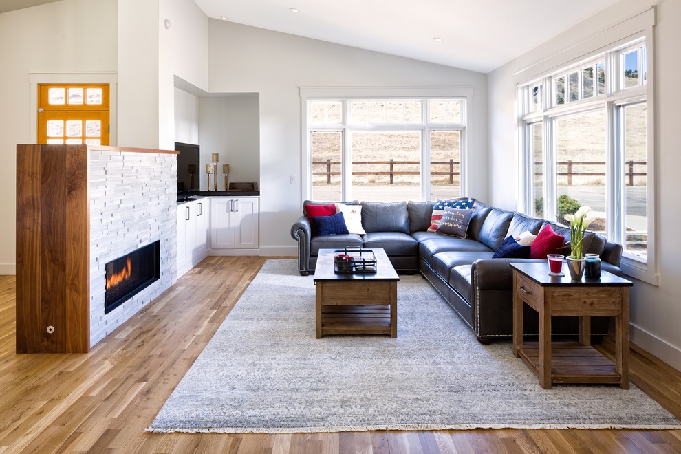 Mid-sized transitional open concept family room in Denver with white walls, light hardwood floors, a two-sided fireplace, a stone fireplace surround, a corner tv and brown floor.
