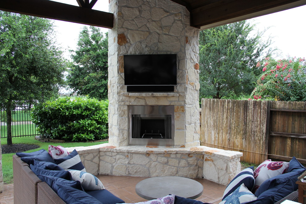 This is an example of a large traditional backyard patio in Houston with a fire feature, stamped concrete and a roof extension.