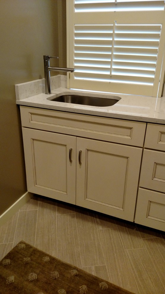 Home design - transitional ceramic tile home design idea with an undermount sink, beige cabinets, quartz countertops, gray walls, a stacked washer/dryer and recessed-panel cabinets