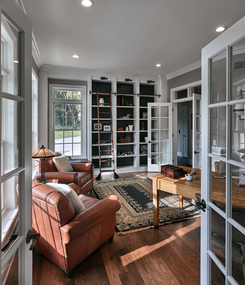 Design ideas for a transitional home office in Other with a library, black walls, medium hardwood floors, a freestanding desk and brown floor.