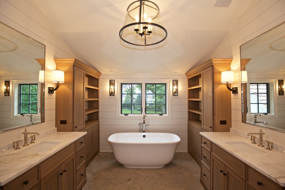 Photo of a mid-sized country master bathroom in Chicago with shaker cabinets, light wood cabinets, a freestanding tub, light hardwood floors, an undermount sink, solid surface benchtops and beige walls.