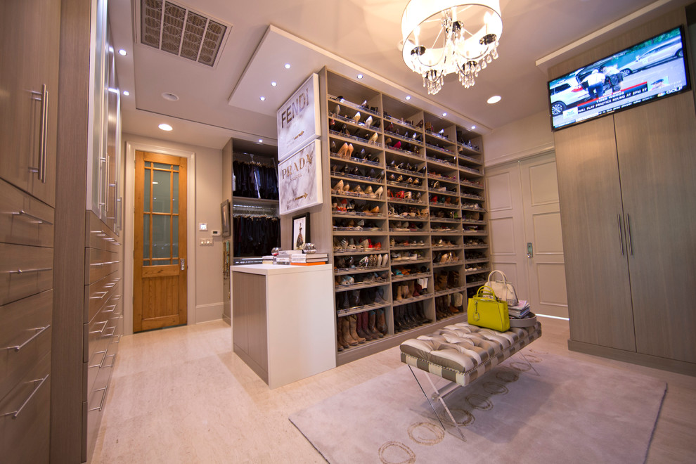 This is an example of an expansive modern women's dressing room in New Orleans with flat-panel cabinets, grey cabinets and travertine floors.