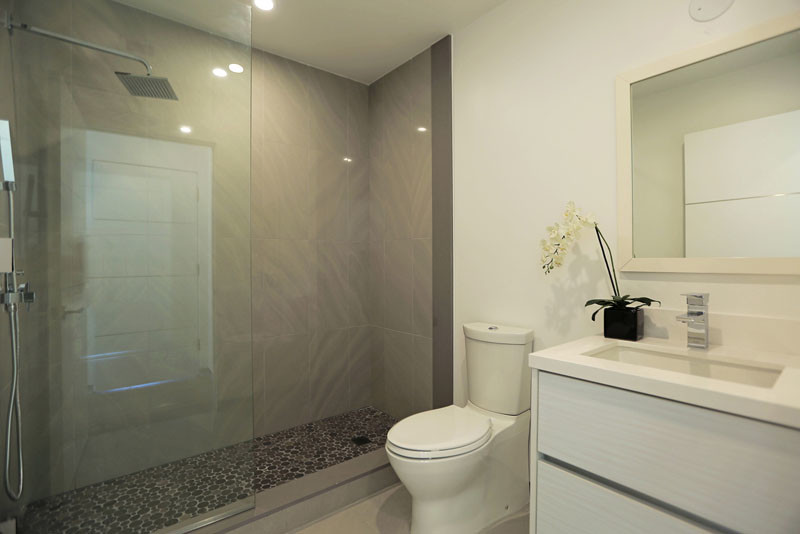 Inspiration for a small modern 3/4 bathroom in Los Angeles with flat-panel cabinets, white cabinets, an alcove shower, a two-piece toilet, pebble tile, white walls, ceramic floors, an integrated sink and solid surface benchtops.