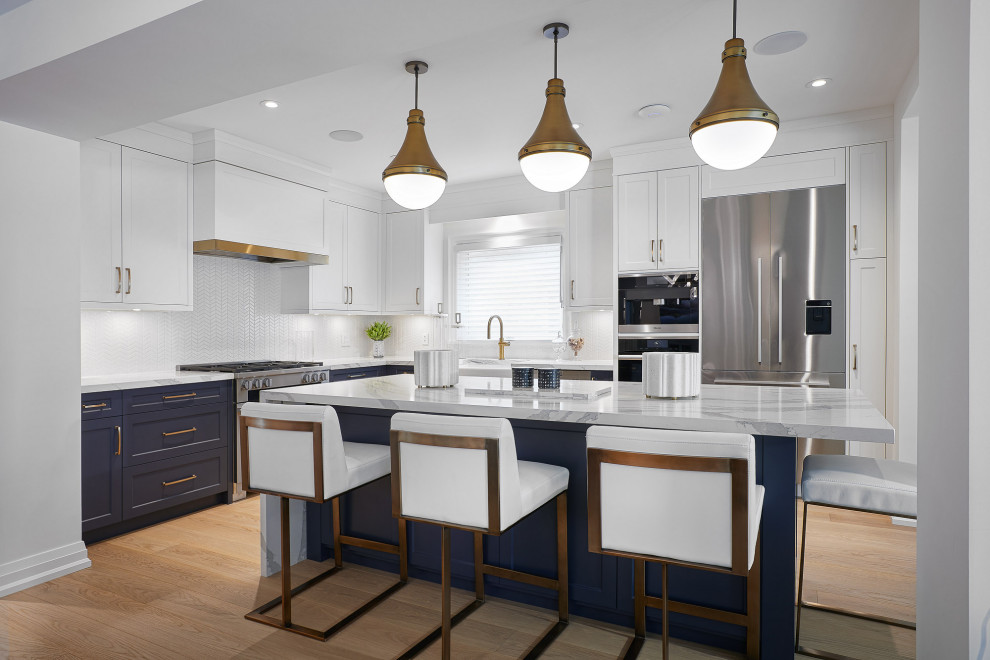 Inspiration for a large transitional l-shaped light wood floor kitchen remodel in Toronto with a farmhouse sink, recessed-panel cabinets, white backsplash, stainless steel appliances, an island and white countertops