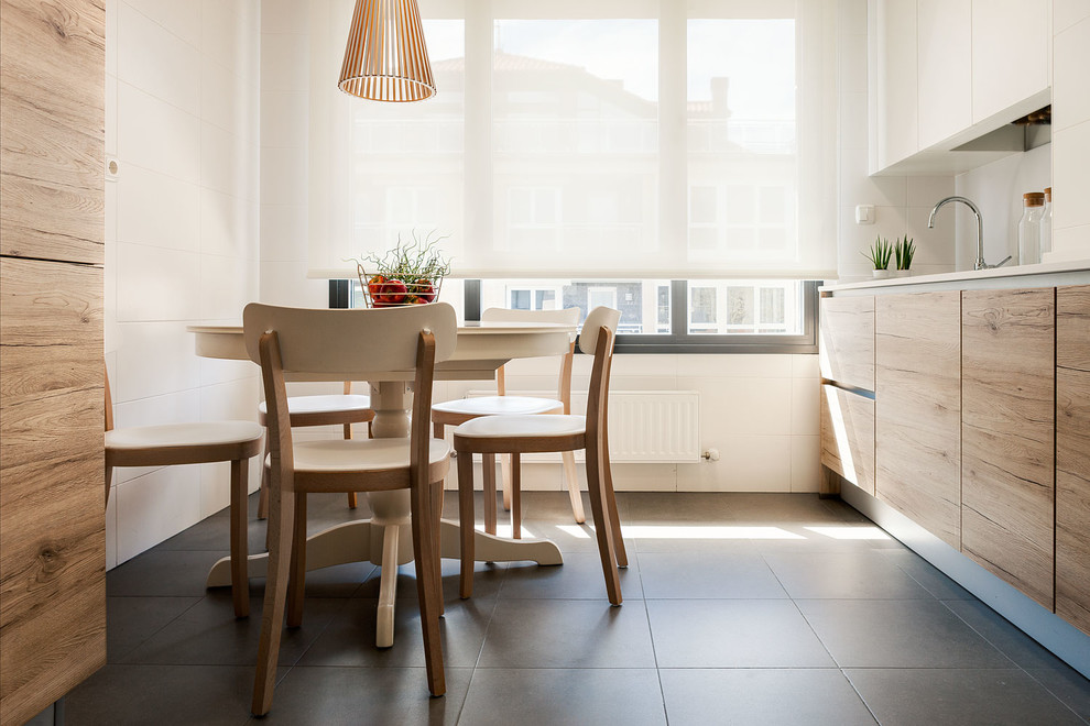 Mid-sized modern single-wall eat-in kitchen in Bilbao with flat-panel cabinets, white splashback, panelled appliances, ceramic floors, a drop-in sink, light wood cabinets, solid surface benchtops and mirror splashback.