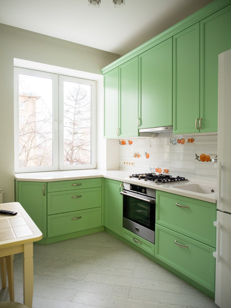 Photo of a small contemporary l-shaped separate kitchen in Moscow with an integrated sink, recessed-panel cabinets, green cabinets, solid surface benchtops, matchstick tile splashback, stainless steel appliances, porcelain floors, no island, grey floor and white splashback.