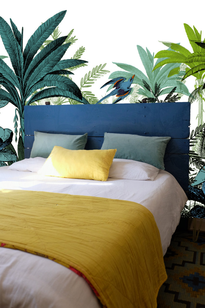 Immagine di una grande camera matrimoniale tropicale con pareti blu, pavimento in laminato e carta da parati