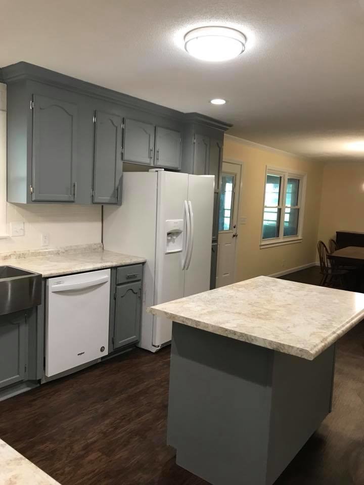 Mid-sized transitional l-shaped medium tone wood floor and brown floor eat-in kitchen photo with a farmhouse sink, shaker cabinets, white cabinets, marble countertops, gray backsplash, stainless steel appliances, an island and gray countertops