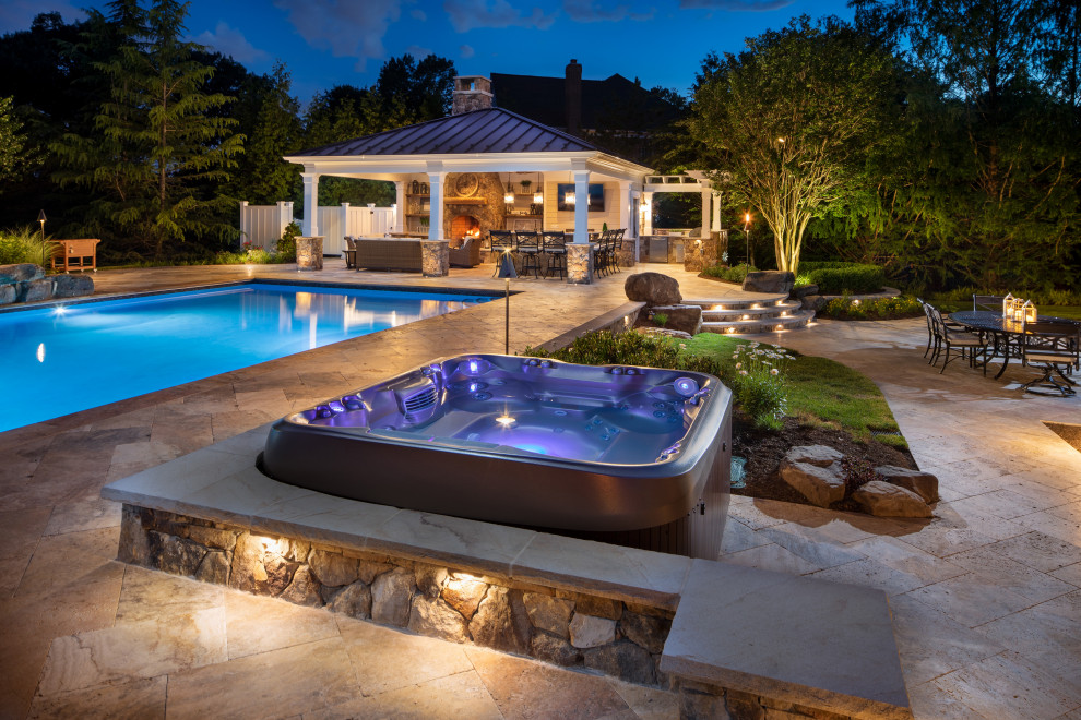 Photo of a mid-sized transitional backyard pool in DC Metro with a hot tub and natural stone pavers.
